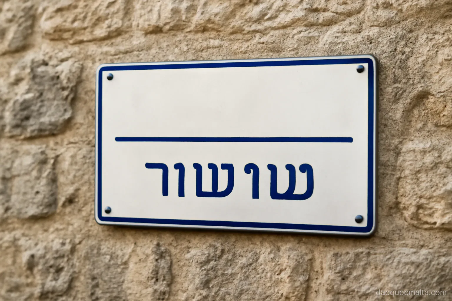 a bilingual street sign on a stone wall showing a place name in two scripts